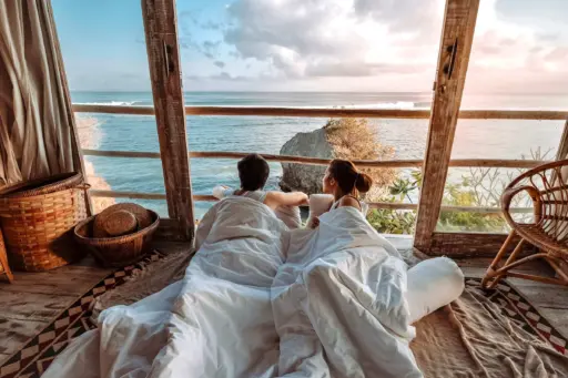 Couple relaxing in bed overlooking the ocean during a romantic Bali getaway