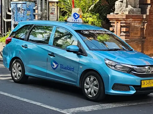 A blue Bluebird taxi parked on a street in Bali with its logo clearly visible on the door, representing a reliable and metered taxi service.