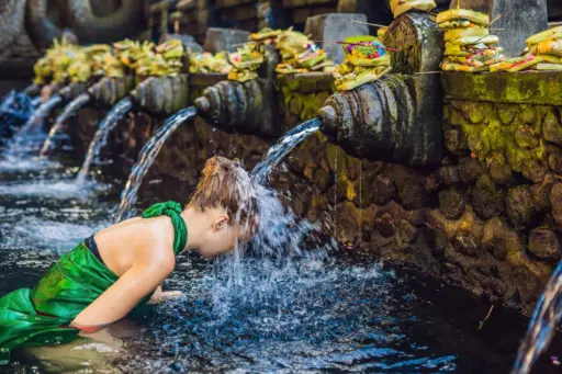 Woman participating in a purification ritual at Bali’s holy spring water temple, symbolizing the spiritual tourism dilemma in Bali